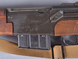 an old machine gun with a wooden handle on a white surface