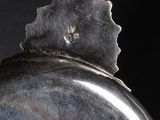 a silver object with a leaf on it