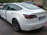a white tesla car parked on the side of the road