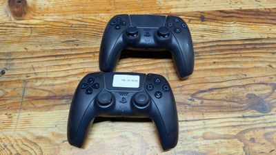 two video game controllers sitting on top of a wooden table