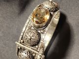 a close up of a silver bracelet with a citrine stone on it