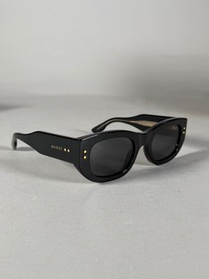 Les lunettes de soleil sont noires et ornées de clous dorés sur les branches.