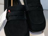 mocassins en daim noir pour homme, avec une boîte blanche posée sur un fond blanc
