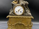 une horloge en or sur laquelle est assis un homme