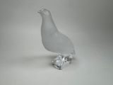 un oiseau en verre posé sur un morceau de verre