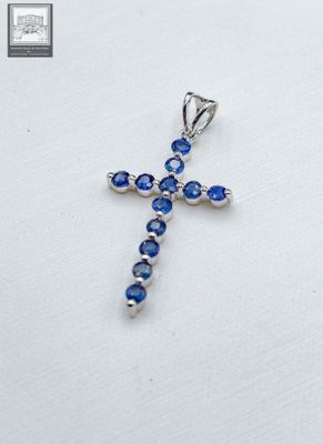 Croix en or blanc 750°/.(18K), ornée de saphirs ronds calibr…