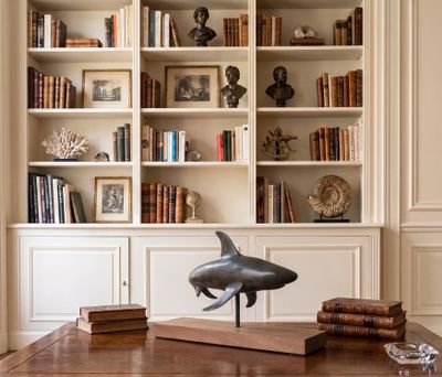 a table with a dolphin statue on it in front of bookshelves