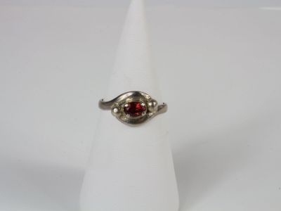 a close up of a ring with a red stone in it