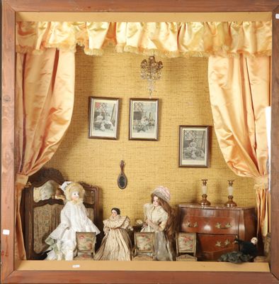 deux poupées dans une vitrine avec des rideaux et des tableaux accrochés au mur