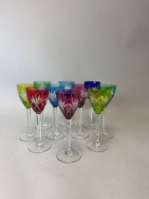 six verres à vin de couleurs différentes sont alignés sur une surface blanche