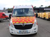 une camionnette rouge et jaune garée sur un parking à côté d'autres camions