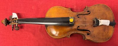 an old violin on a red cloth with a bow on top of it