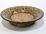 un bol marron et noir posé sur une table blanche