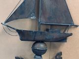 a metal weather vane with a sailboat on it