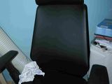 une chaise de bureau noire avec une assise noire, près d'un mur bleu