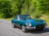 a green car driving down the road with trees in the background