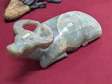 une statue d'éléphant assis sur une table, à côté d'une paire de chaussures