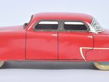 a red toy car that is sitting on a white surface