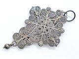 a close up of a silver pendant on a white surface