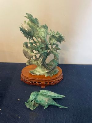 une statue représentant un oiseau posée sur une table, à côté d'un vase