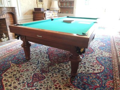 une table de billard dans un salon avec un tapis au sol