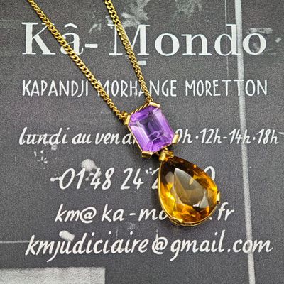pendentif en cristal jaune et violet, monté sur une chaîne en or, présenté sur une carte de visite