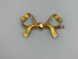 broche en forme de nœud doré avec un ruban torsadé sur fond blanc