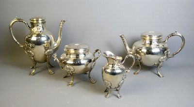 three silver teapots and a coffee pot on a table