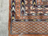 an orange and blue rug on a cement floor with a cat sitting on top of it