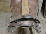 une vieille chaise en bois avec une assise en cuir, posée sur un socle