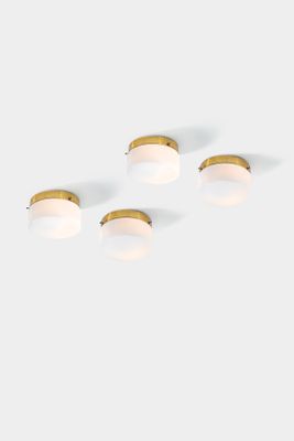 a set of four brass and glass wall lights on a white background