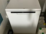 a small white dishwasher in the corner of a bathroom
