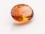 a close up of a faceted citrine gemstone on a white surface