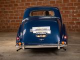 a blue car parked in front of a brick wall
