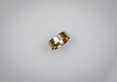 gros plan d'une bague en or sur une surface blanche
