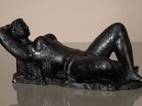 statue of a woman reclining on a rock on a glass table