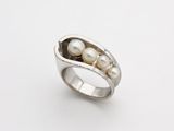 a close up of two peas in a pod ring on a white surface