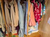 une armoire pleine de vêtements et un vase posé par terre