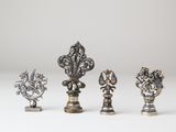 a group of four silver chess pieces on a white surface