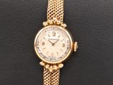a close up of a gold wrist watch on a black cushion