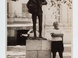 black and white photograph of a man standing next to a statue of a man holding a tennis racquet