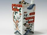 un vase blanc et rouge orné d'un oiseau