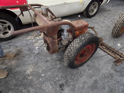 un vieux tracteur équipé d'un petit moteur, garé sur un parking