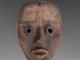 a close up of a wooden mask on a gray background