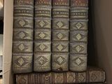 Plusieurs vieux livres sont empilés dans une boîte en carton posée sur une table