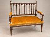 un vieux banc en bois dont l'assise est recouverte de velours jaune