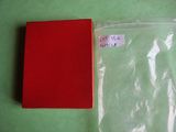 a red book sitting on a green surface next to a plastic bag