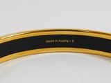 a close up of a black and gold bracelet on a white surface