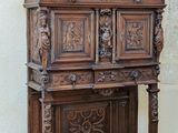 a wooden cabinet with carvings on the front and a potted plant on top of it