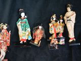 five figurines of asian women on display on a black background